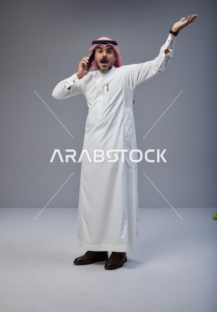 رجل سعودي بالزي التقليدي يتحدث عبر الهاتف الجوال