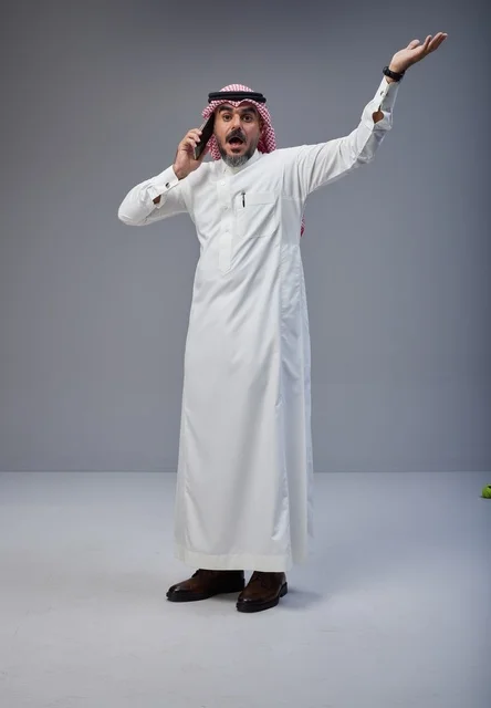 رجل سعودي بالزي التقليدي يتحدث عبر الهاتف الجوال