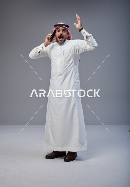 رجل سعودي بالزي التقليدي مصدوم يتحدث بالهاتف