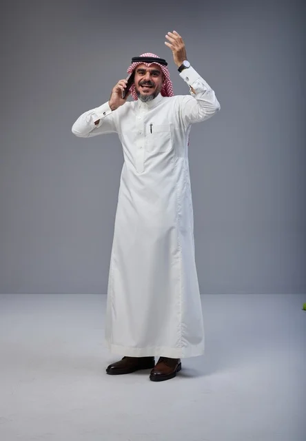 Saudi Man in Traditional Thobe Talking on Smartphone