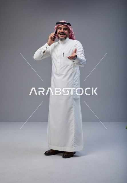 رجل سعودي بالزي التقليدي يتحدث عبر الهاتف المحمول