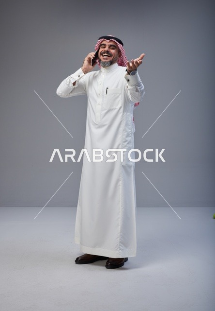 رجل سعودي بالزي التقليدي يتحدث عبر الهاتف المحمول