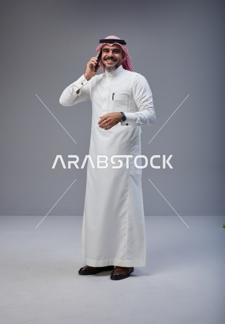 رجل سعودي بالزي التقليدي يتحدث عبر الهاتف الجوال