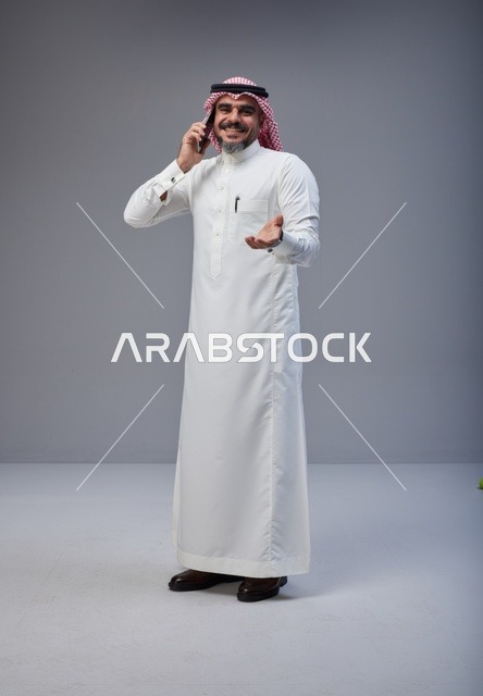 رجل سعودي بالزي التقليدي يتحدث عبر الهاتف الذكي