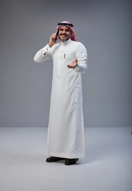 رجل سعودي بالزي التقليدي يتحدث عبر الهاتف الذكي