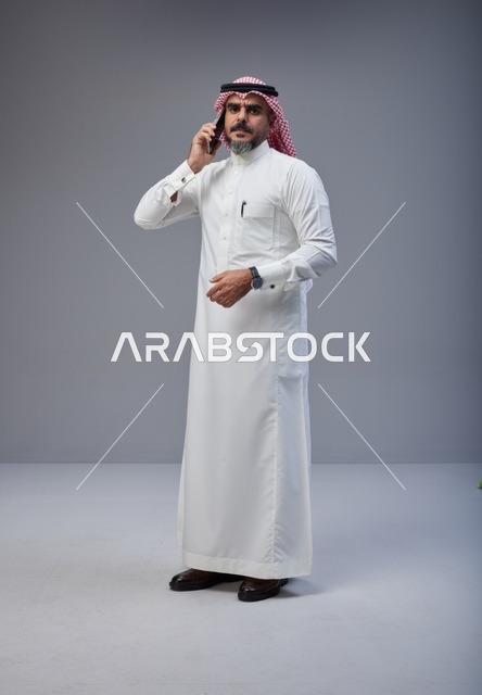 Saudi Man in Traditional Thobe Talking on Mobile Phone
