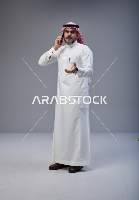 رجل سعودي بالزي التقليدي يتحدث عبر الهاتف الجوال