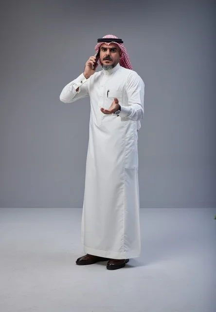 رجل سعودي بالزي التقليدي يتحدث عبر الهاتف الجوال
