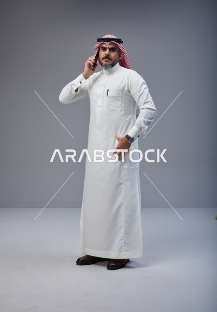 Saudi Man in Traditional Thobe Talking on Smartphone
