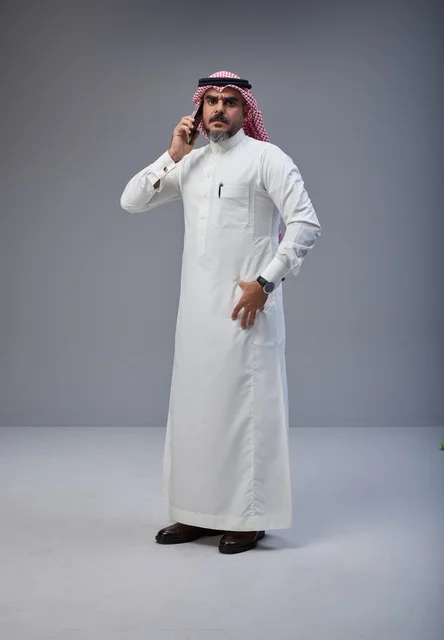 رجل سعودي بالزي التقليدي يتحدث عبر الهاتف الجوال