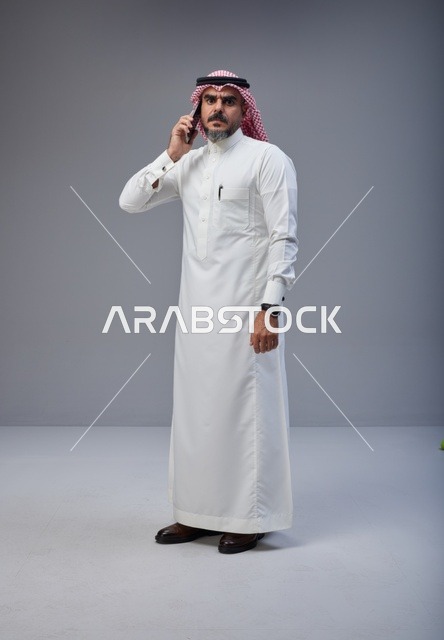 رجل سعودي بالزي التقليدي يتحدث عبر الهاتف الجوال