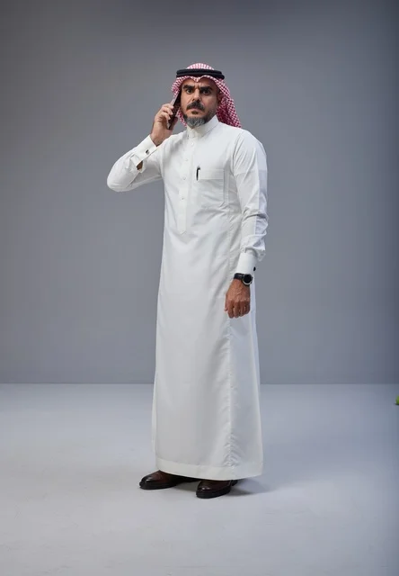 رجل سعودي بالزي التقليدي يتحدث عبر الهاتف الجوال