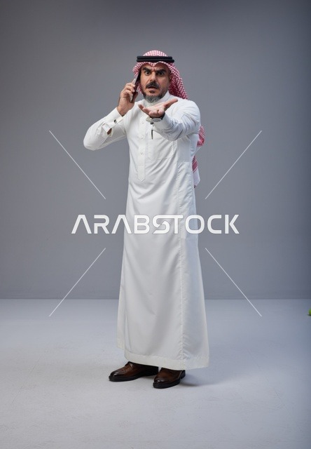 رجل سعودي يتحدث عبر الهاتف الجوال بتعبير غاضب