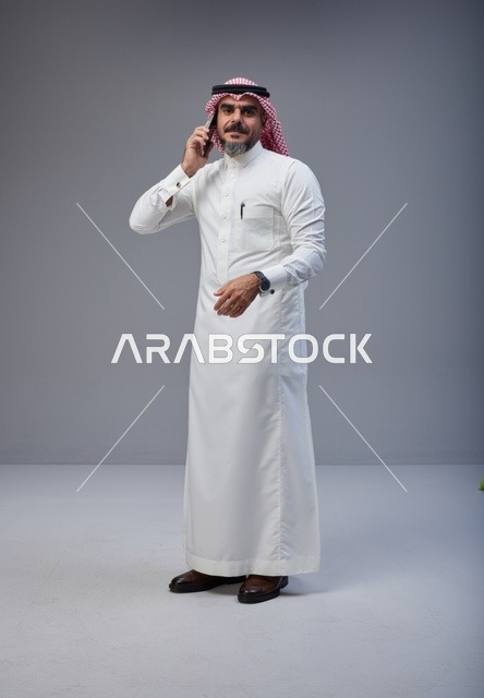 Saudi Man in Traditional Thobe Talking on Smartphone