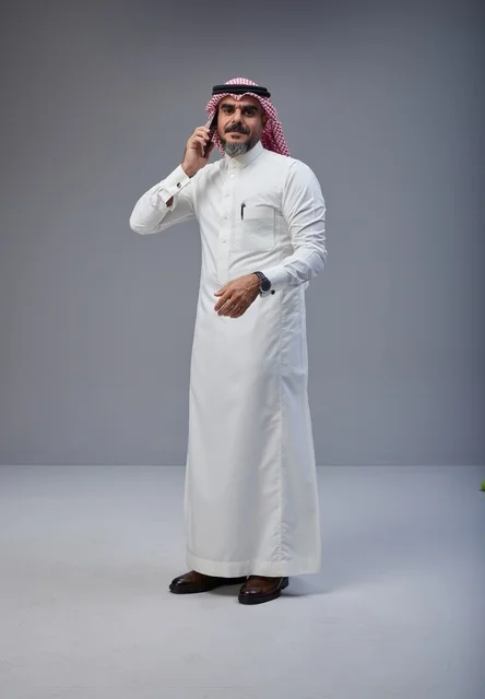 Saudi Man in Traditional Thobe Talking on Smartphone