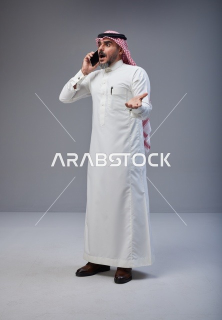 رجل سعودي بالزي التقليدي متفاجئ يتحدث عبر الهاتف