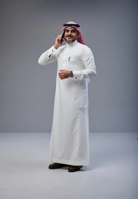 Saudi Man in Traditional Thobe Talking on Smartphone