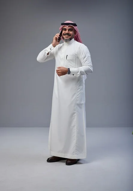 رجل سعودي بالزي التقليدي يتحدث عبر الهاتف الجوال