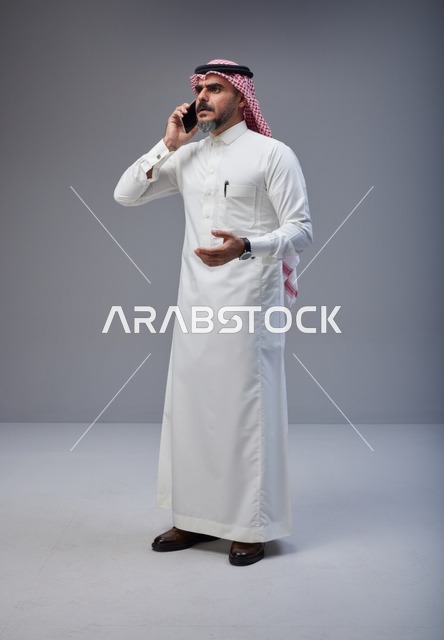 رجل سعودي بالزي التقليدي يتحدث عبر الهاتف المحمول