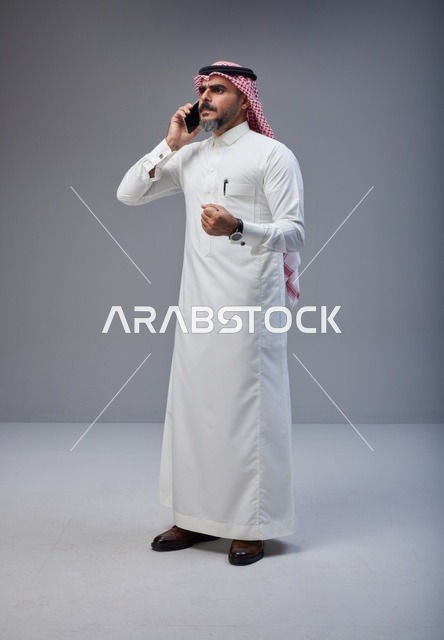 Saudi Man in Traditional Thobe Talking on Smartphone