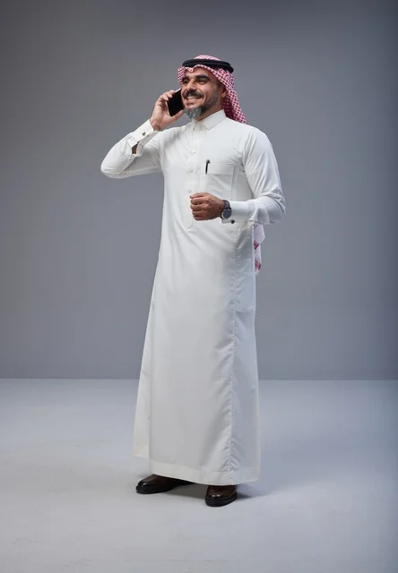 Saudi Man in Traditional Attire Using Smartphone in Studio
