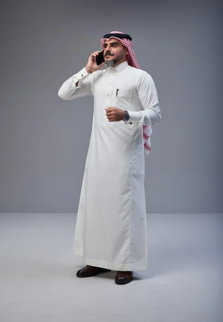 رجل سعودي بالزي التقليدي يتحدث عبر الهاتف الذكي