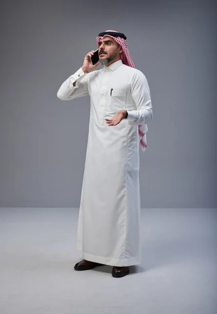 Saudi Man in Traditional Dress Talking on Smartphone