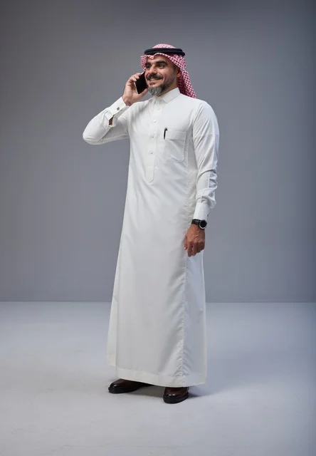 Saudi man in traditional attire talking on smartphone