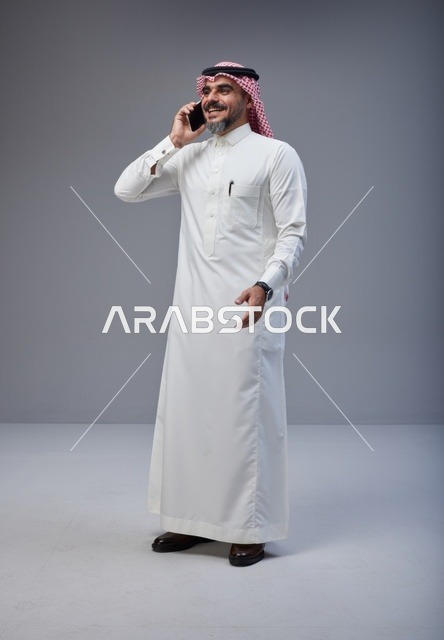 رجل سعودي بالزي التقليدي يتحدث عبر الهاتف الجوال