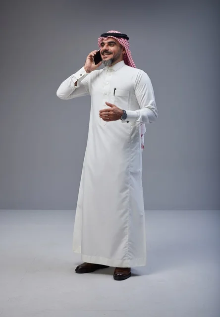 Saudi man in traditional attire talking on smartphone