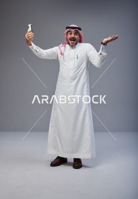 رجل سعودي بالزي التقليدي يلتقط صورة سيلفي بتعجب