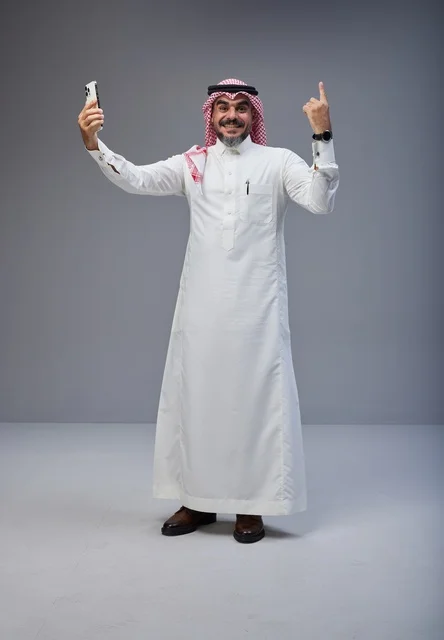 رجل سعودي بالزي التقليدي يلتقط صورة سيلفي بالجوال