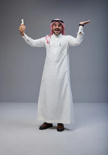 رجل سعودي بالزي التقليدي يلتقط صورة سيلفي بحماس