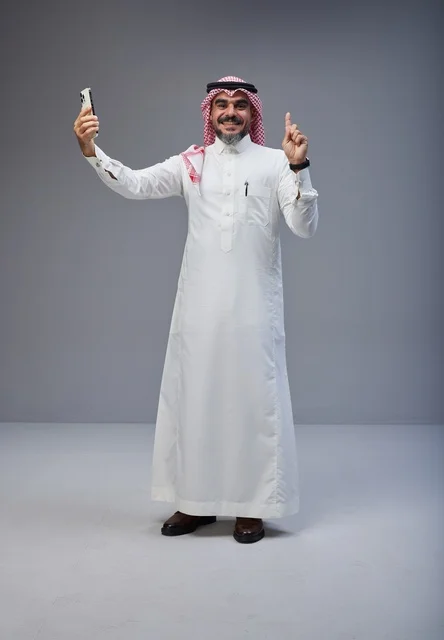 رجل سعودي بالزي التقليدي يلتقط صورة سيلفي في الاستوديو