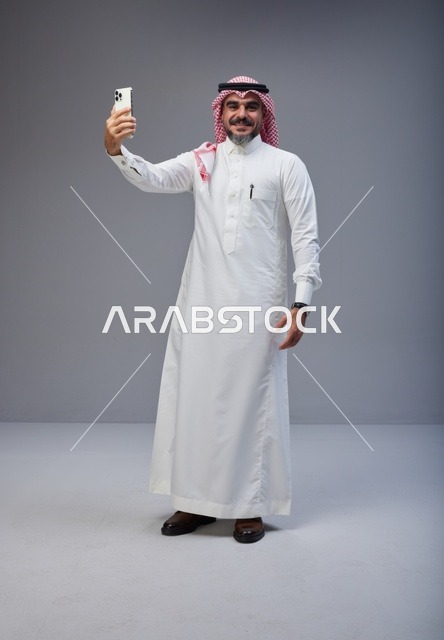 رجل سعودي بالزي التقليدي يلتقط سيلفي بالهاتف