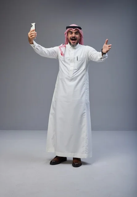 رجل سعودي بالزي التقليدي يلتقط صورة سيلفي بحماس