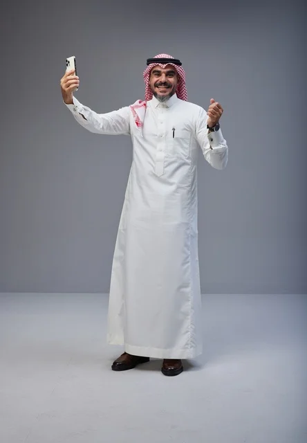 رجل سعودي بالزي التقليدي يلتقط صورة سيلفي بالجوال