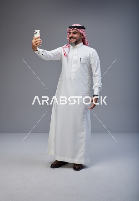 رجل سعودي بالزي التقليدي يلتقط صورة سيلفي
