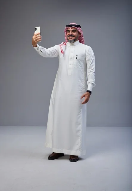 رجل سعودي بالزي التقليدي يلتقط صورة سيلفي في الاستوديو
