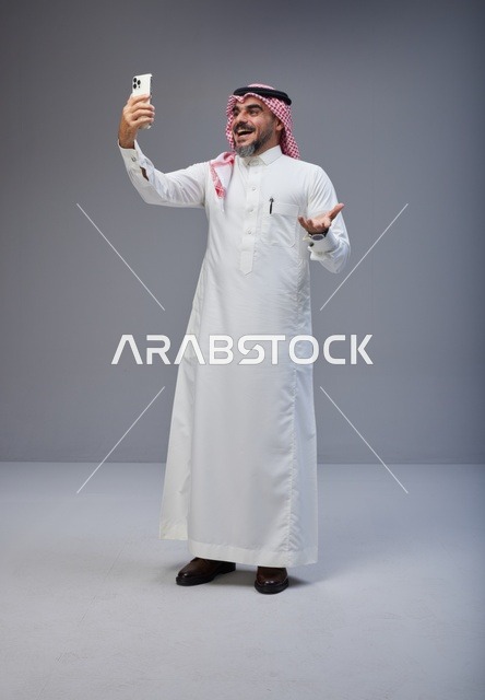رجل سعودي بالزي التقليدي يلتقط صورة سيلفي بالجوال