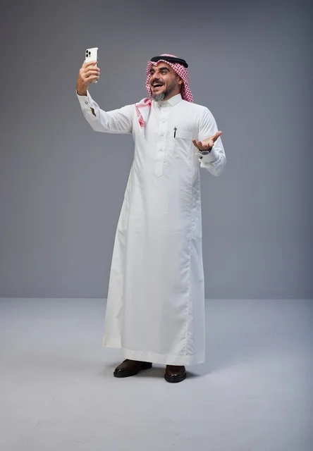 رجل سعودي بالزي التقليدي يلتقط صورة سيلفي بالجوال