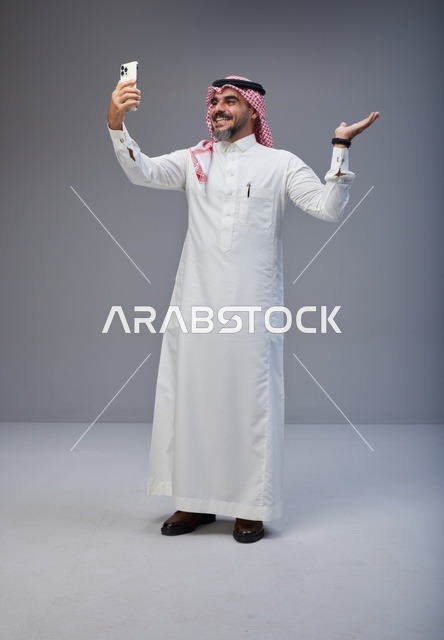 رجل سعودي بالزي التقليدي يلتقط صورة سيلفي بالجوال