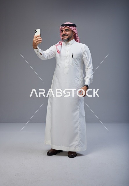 رجل سعودي بالزي التقليدي يلتقط صورة سيلفي بالجوال