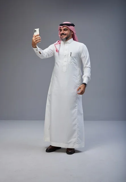 رجل سعودي بالزي التقليدي يلتقط صورة سيلفي بالجوال
