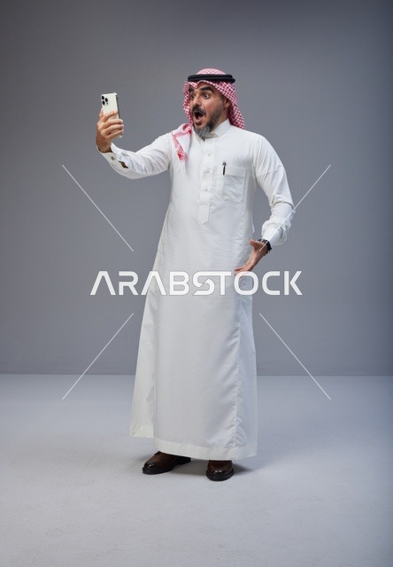 رجل سعودي بالزي التقليدي يعبر عن مفاجأته بالهاتف