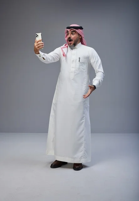رجل سعودي بالزي التقليدي يعبر عن مفاجأته بالهاتف