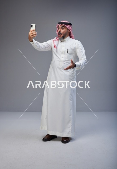 رجل سعودي بالزي التقليدي يلتقط صورة سيلفي باستوديو