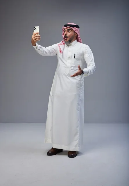 رجل سعودي بالزي التقليدي يلتقط صورة سيلفي باستوديو