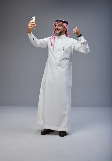 Saudi Man in Traditional Thobe Taking Selfie with Thumbs Up
