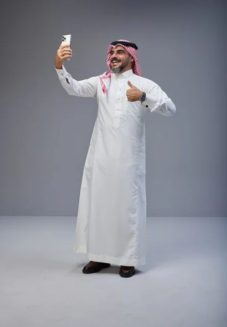 رجل سعودي بالزي التقليدي يلتقط سيلفي في الاستوديو